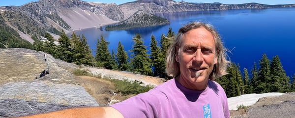 Eric poses in front of a lake lined by trees